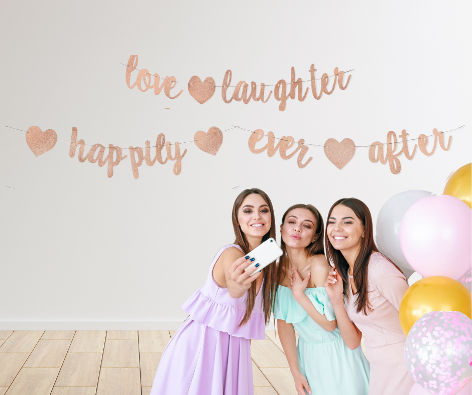 Three women taking a selfie with balloons and a "Love, Laughter, Happily Ever After" decorative banner in the background.