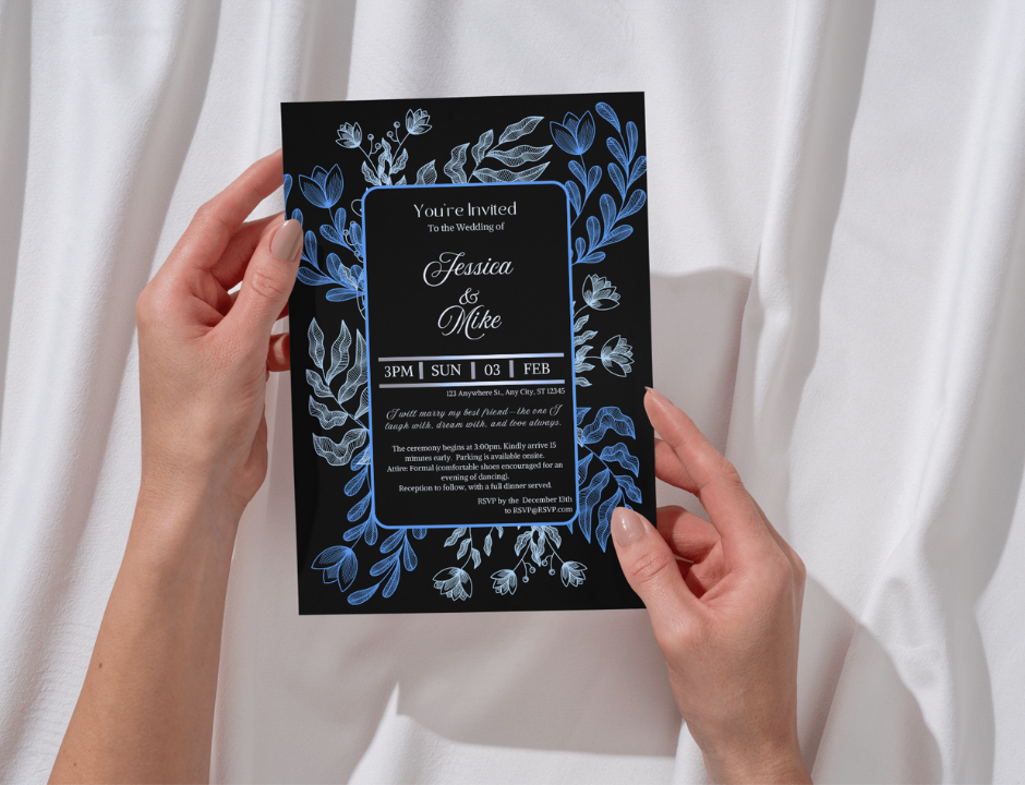 Hand holding a wedding invitation card with blue floral designs on a white background