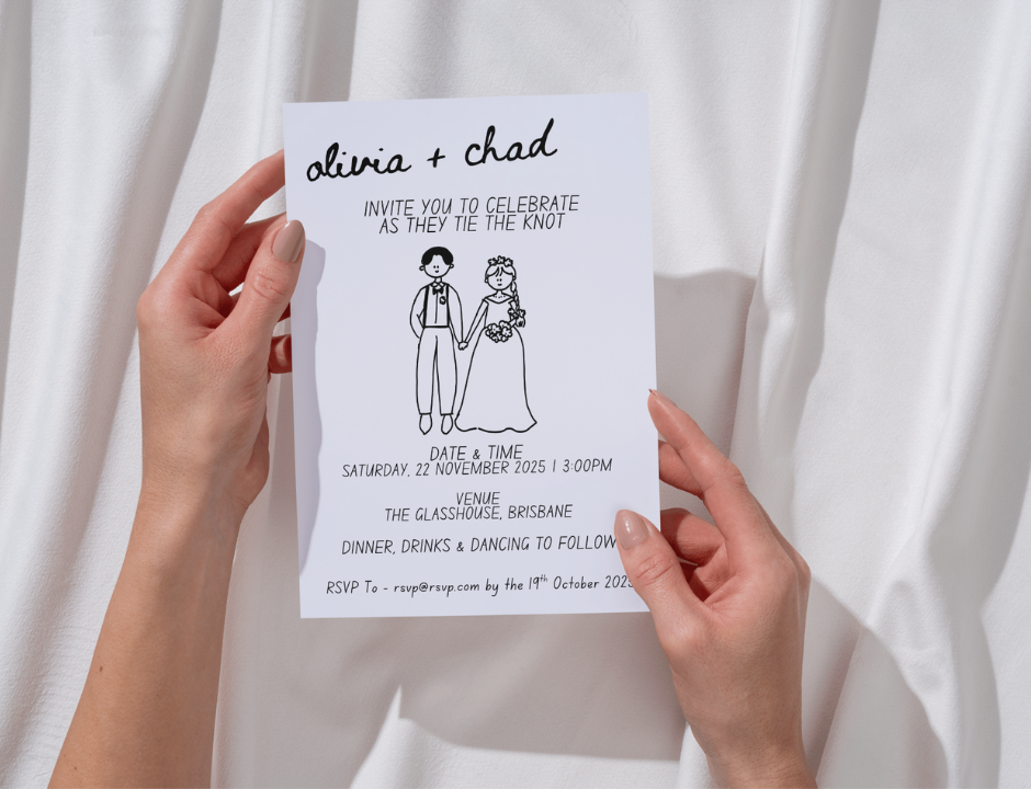 Hand holding a wedding invitation with a couple illustration against a white curtain background