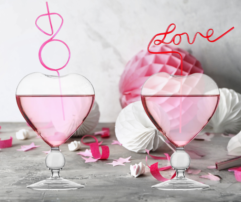 Two heart-shaped glasses with pink liquid, 'love' decoration, and diamond-shaped straws