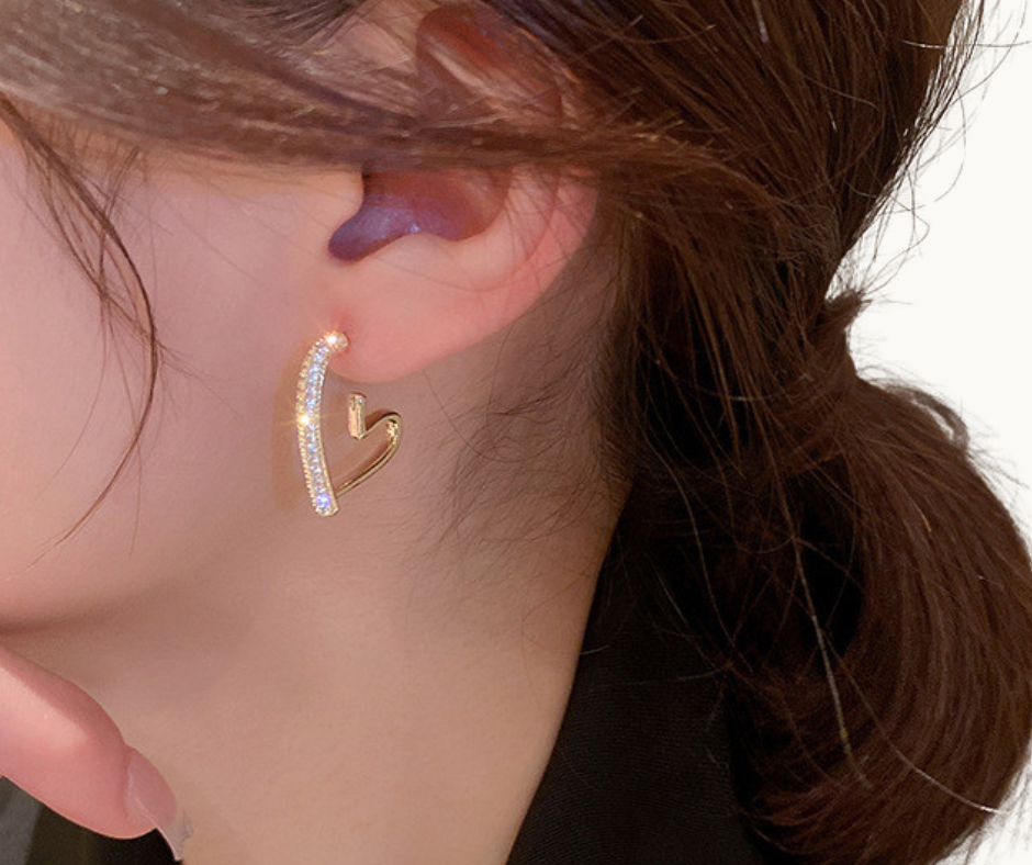 Close-up of a person wearing a gold heart hoop earring