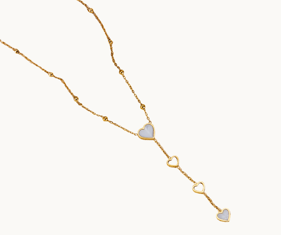 Gold pearl shell necklace with heart-shaped pendants on a white background