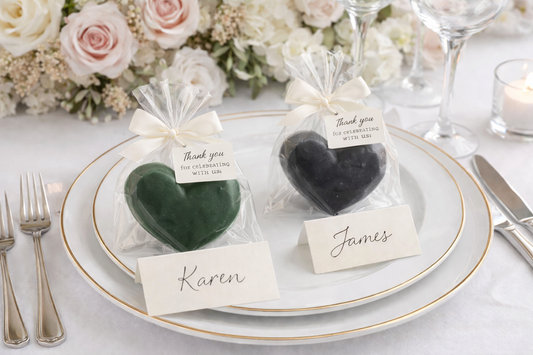 Heart-shaped favors on a place setting with floral arrangements and candles.