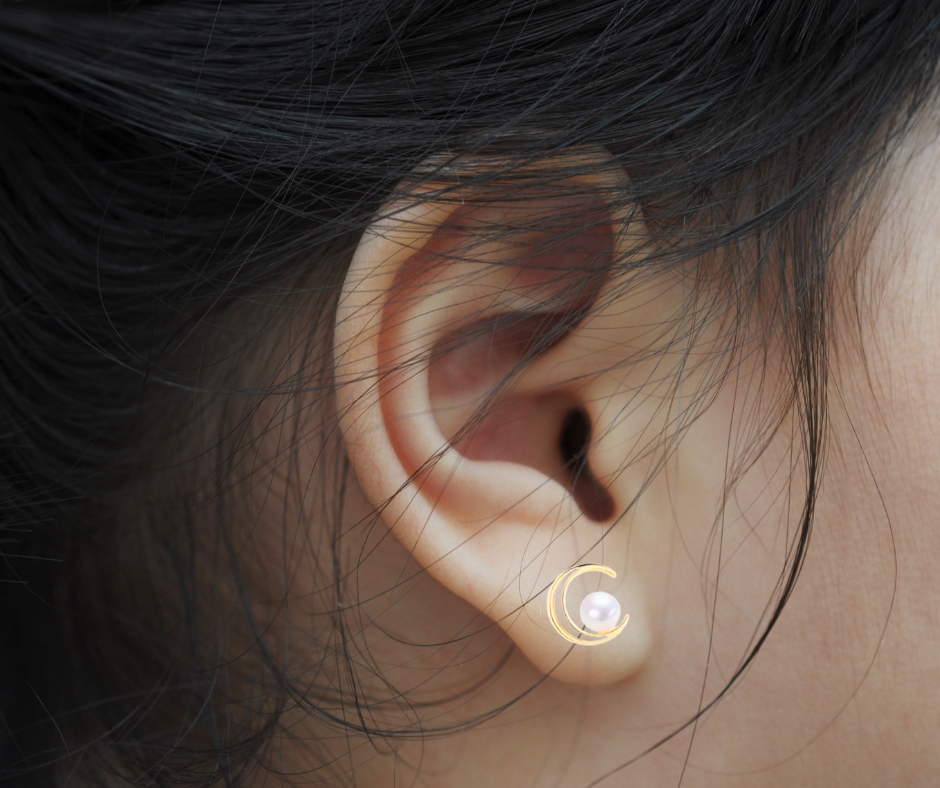 Close-up of an ear with a gold moon shape pearl earring