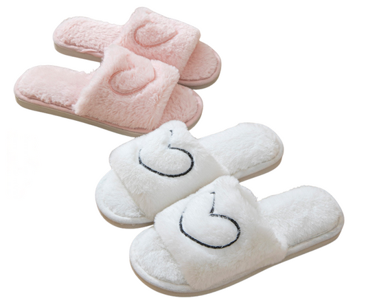 Pair of pink and white slippers with heart design on a white background