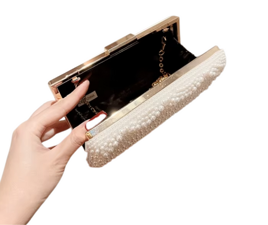 Hand holding a pearl clutch bag on a white background