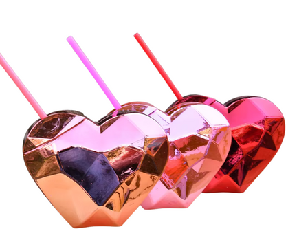 Heart-shaped metallic drink holders with straws on a white background