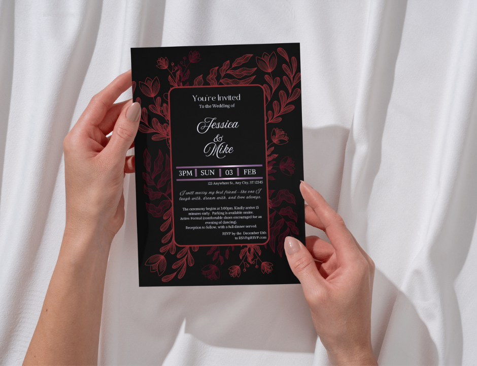 Hand holding a wedding invitation card with red floral design on a white background