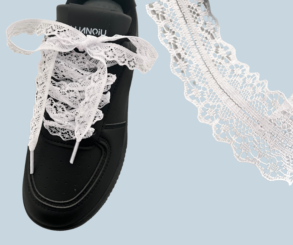 Black sneaker with white lace shoelaces on a light blue background