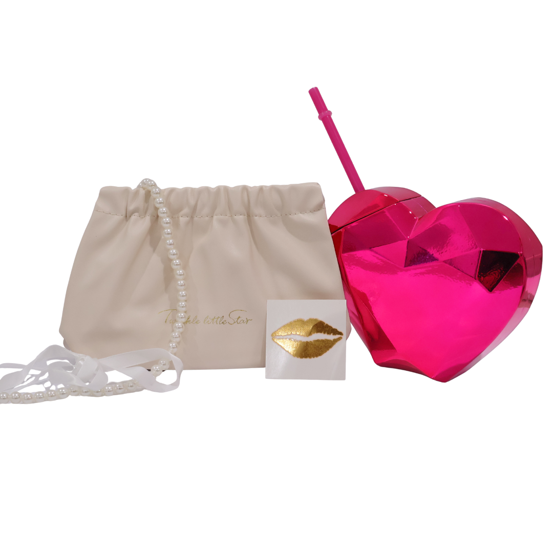 Pink heart-shaped tumbler with straw, beige makeup bag, ribbon choker and metallic gold tattoo on a white background