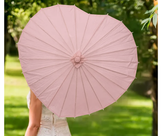 Person holding a pink heart shaped parasol against a green outdoor background