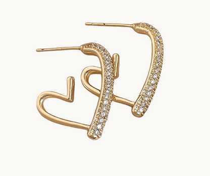 Gold earrings with heart design and clear stones on a white background