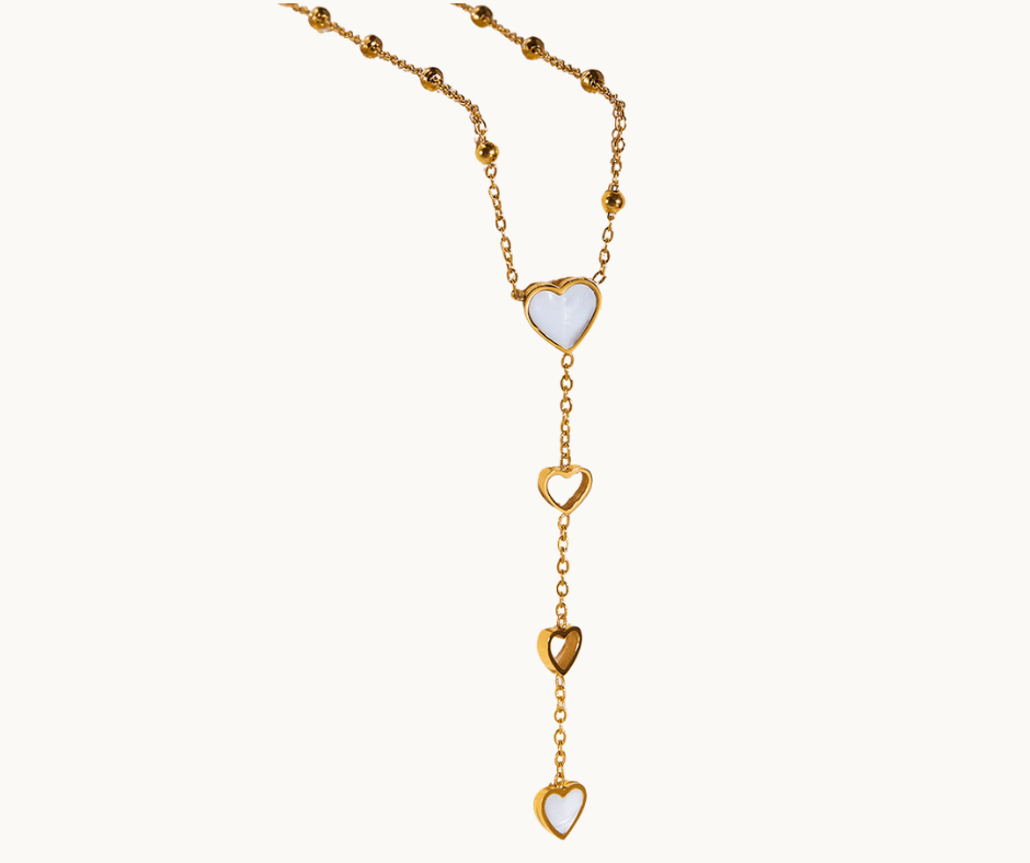 Gold pearl shell necklace with heart-shaped pendants on a white background