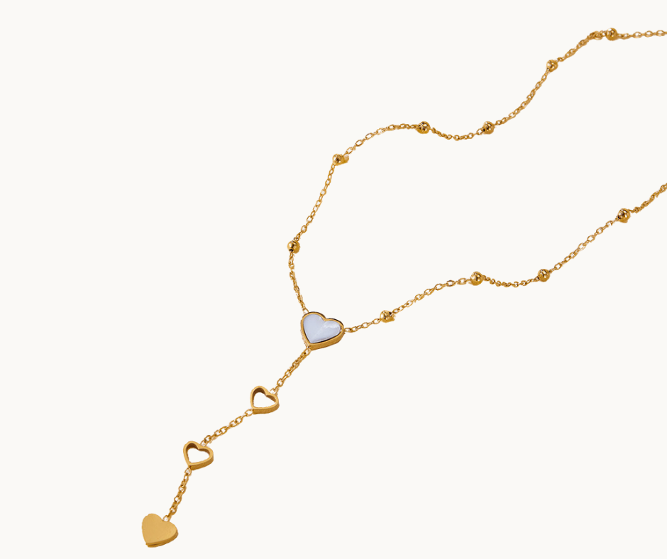 Gold pearl shell necklace with heart-shaped pendants on a white background