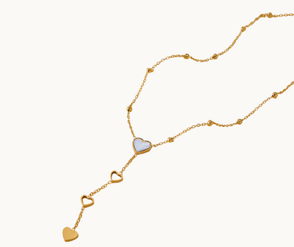 Gold pearl shell necklace with heart-shaped pendants on a white background