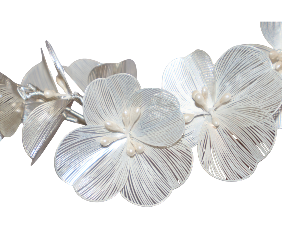 Close up of White floral hair piece with pearl centres on a white background