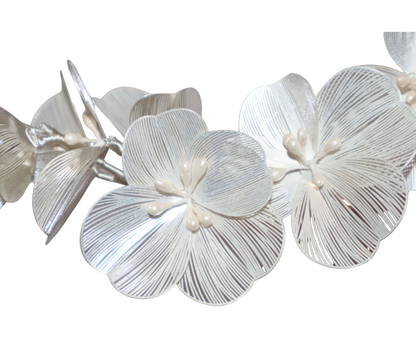 Close up of White floral hair piece with pearl centres on a white background