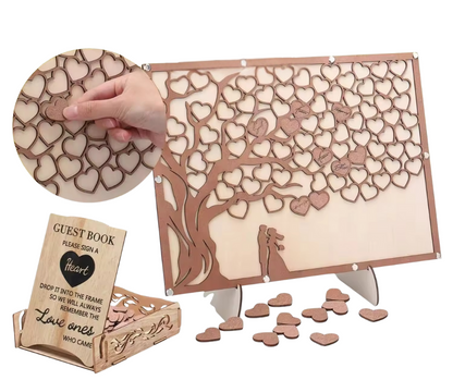Wooden heart-shaped guest book with hearts and a tree design, including a hand holding a heart and a small box labeled 'Guest Book'.