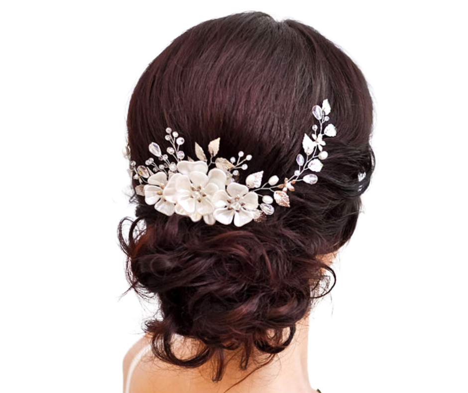Bride with dark hair styled in an updo wearing a floral hairpiece on a white background
