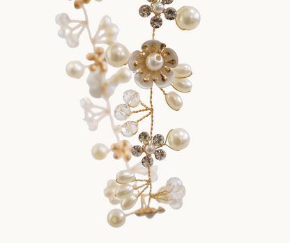 Decorative floral hair vine with pearls and gold elements on a white background