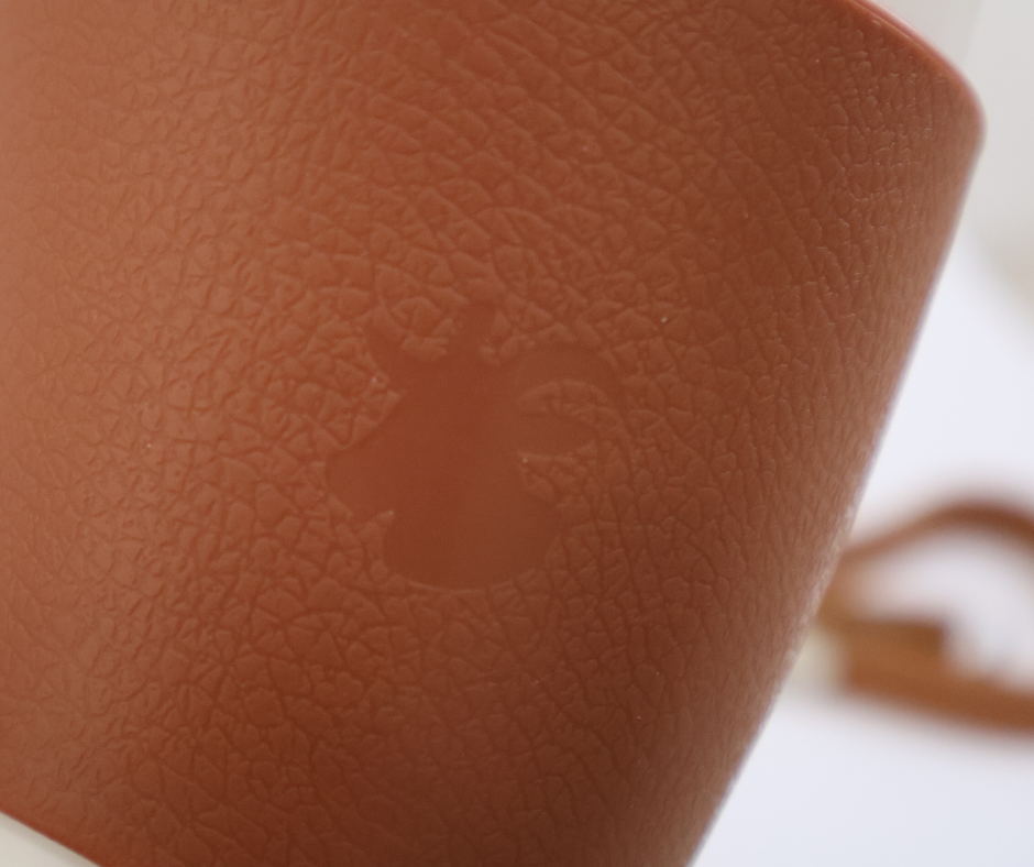Close-up of a brown textured mug sleeve with a goat logo on a white background
