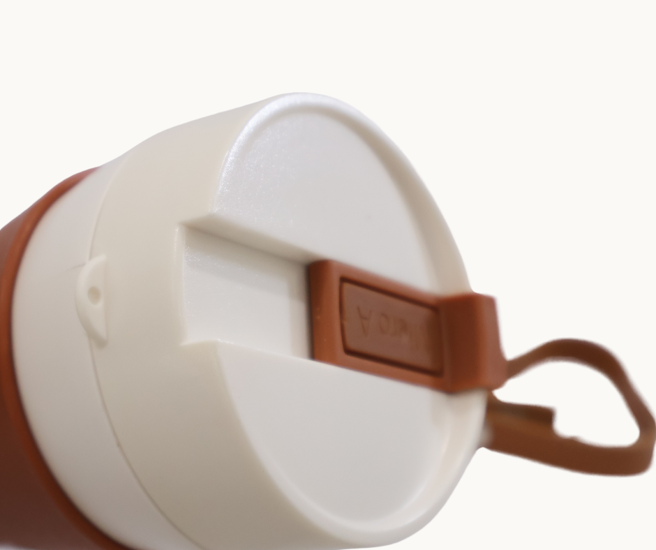 Close up of White horn travel mug with brown handle and lid on a white background
