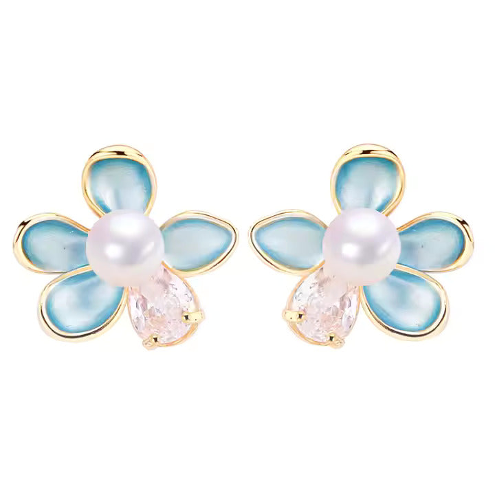 Flower-shaped earrings with pearl and gemstone center on a white background