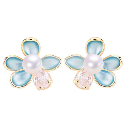 Flower-shaped earrings with pearl and gemstone center on a white background