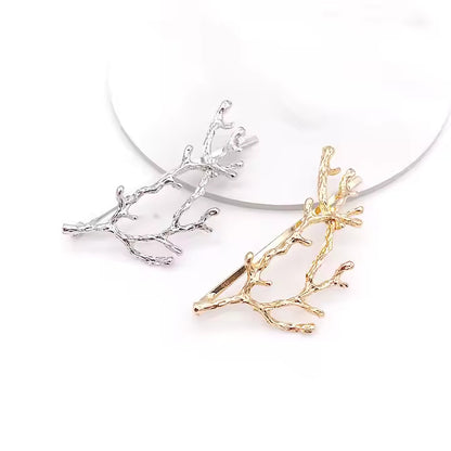 Silver and gold branch-shaped hair clips on a white background