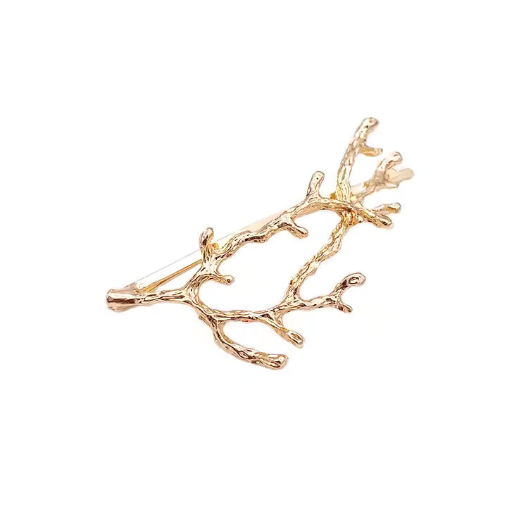 Gold branch-shaped hair pin on a white background