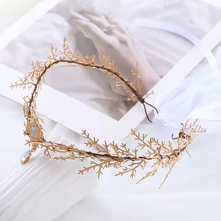 Gold leaf headpiece on a white surface with a blurred background