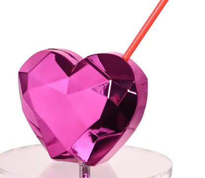 Pink heart-shaped tumbler with a red straw on a white background
