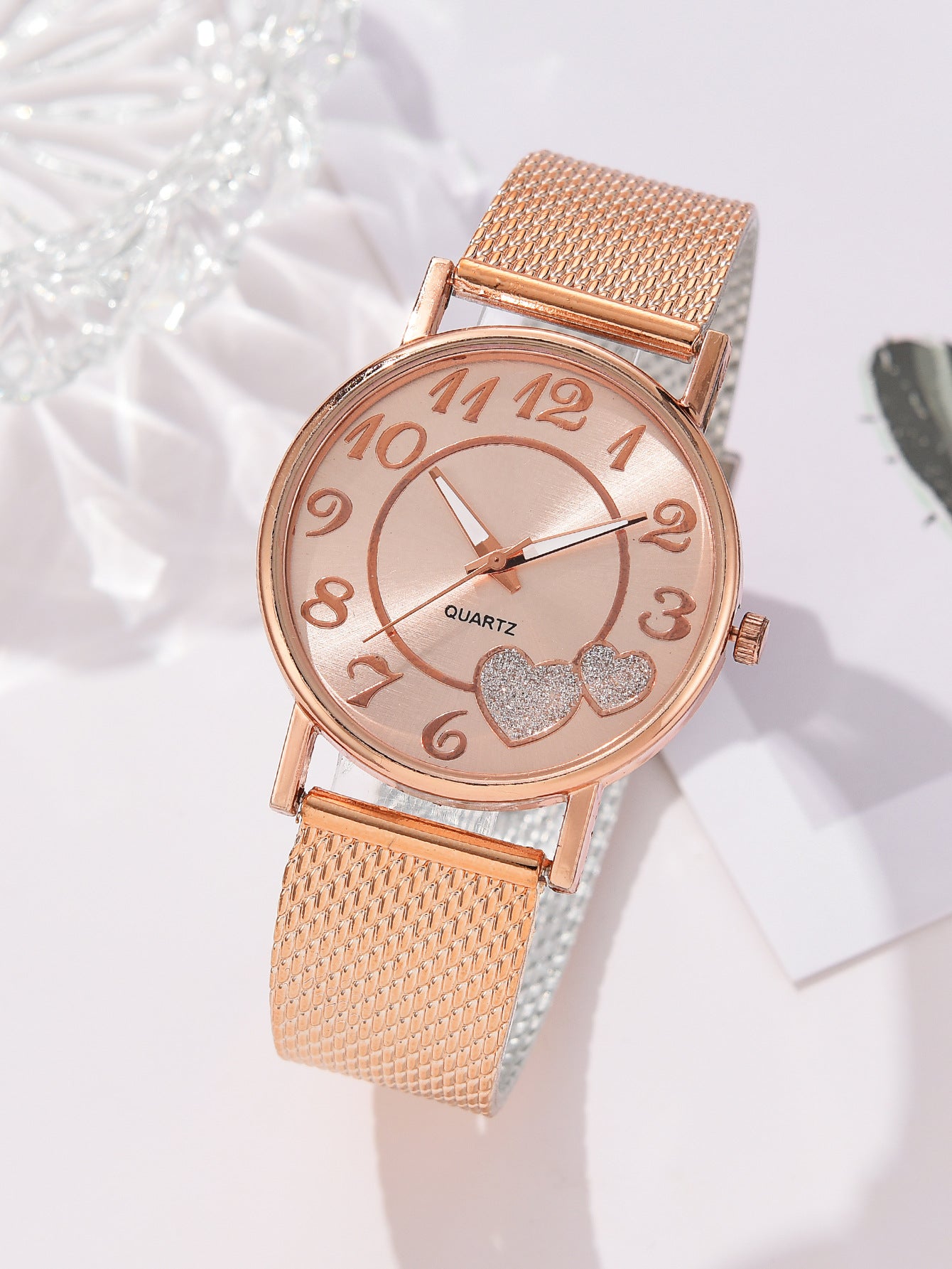Rose gold watch with heart details on a white background