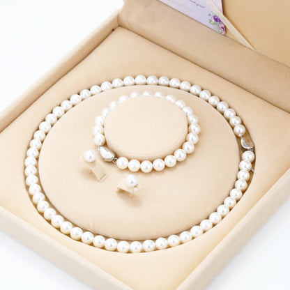 Pearl necklace and bracelet set in a beige jewelry box on a white background