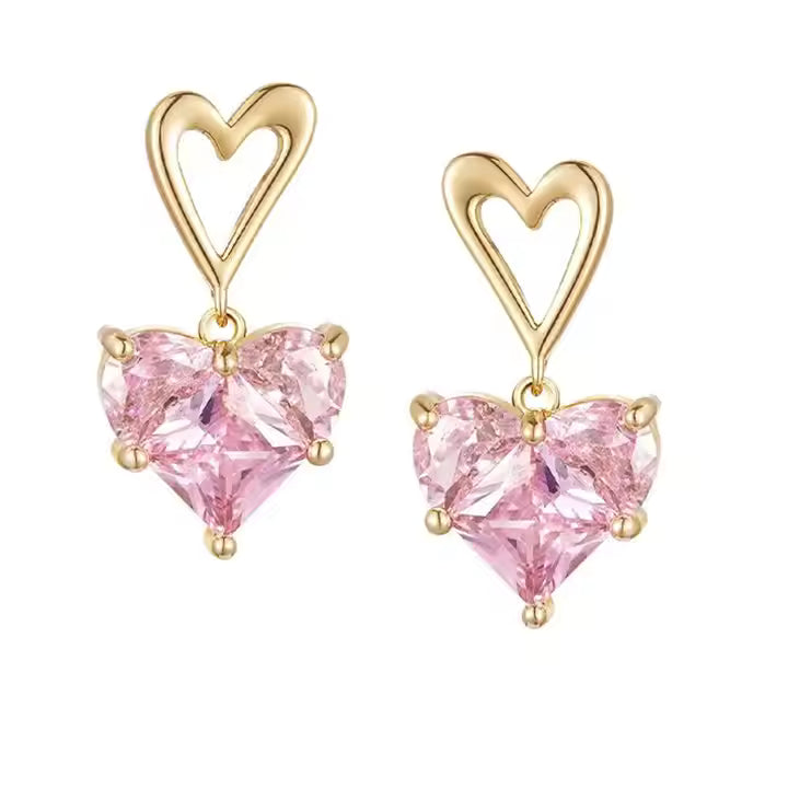 Gold heart-shaped earrings with pink gemstones on a white background