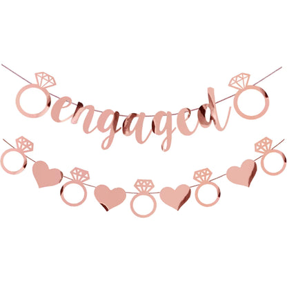Rose gold 'engaged' banner with rings and hearts on a white background
