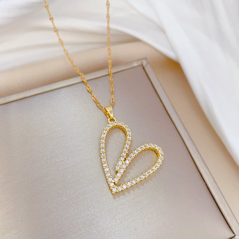Gold heart-shaped necklace with clear stones on a light background