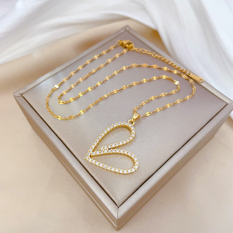 Gold necklace with a heart-shaped pendant on a beige box