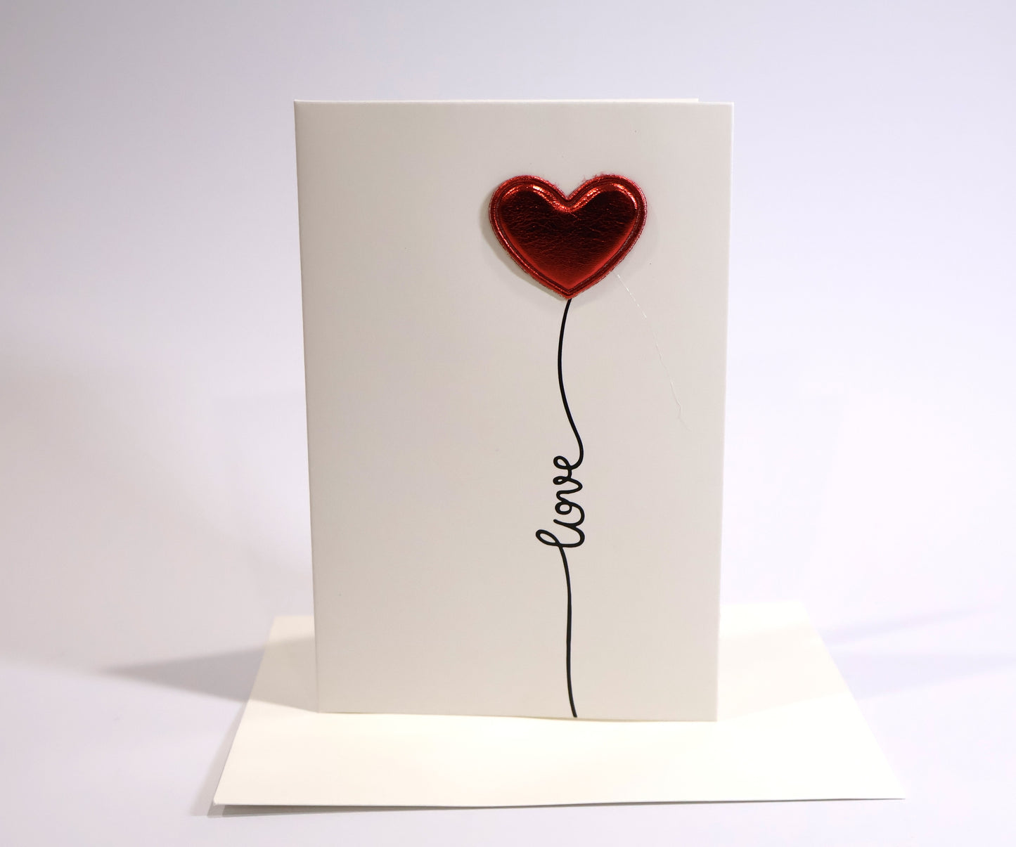 Card with a red heart-shaped balloon and 'love' text on a white background
