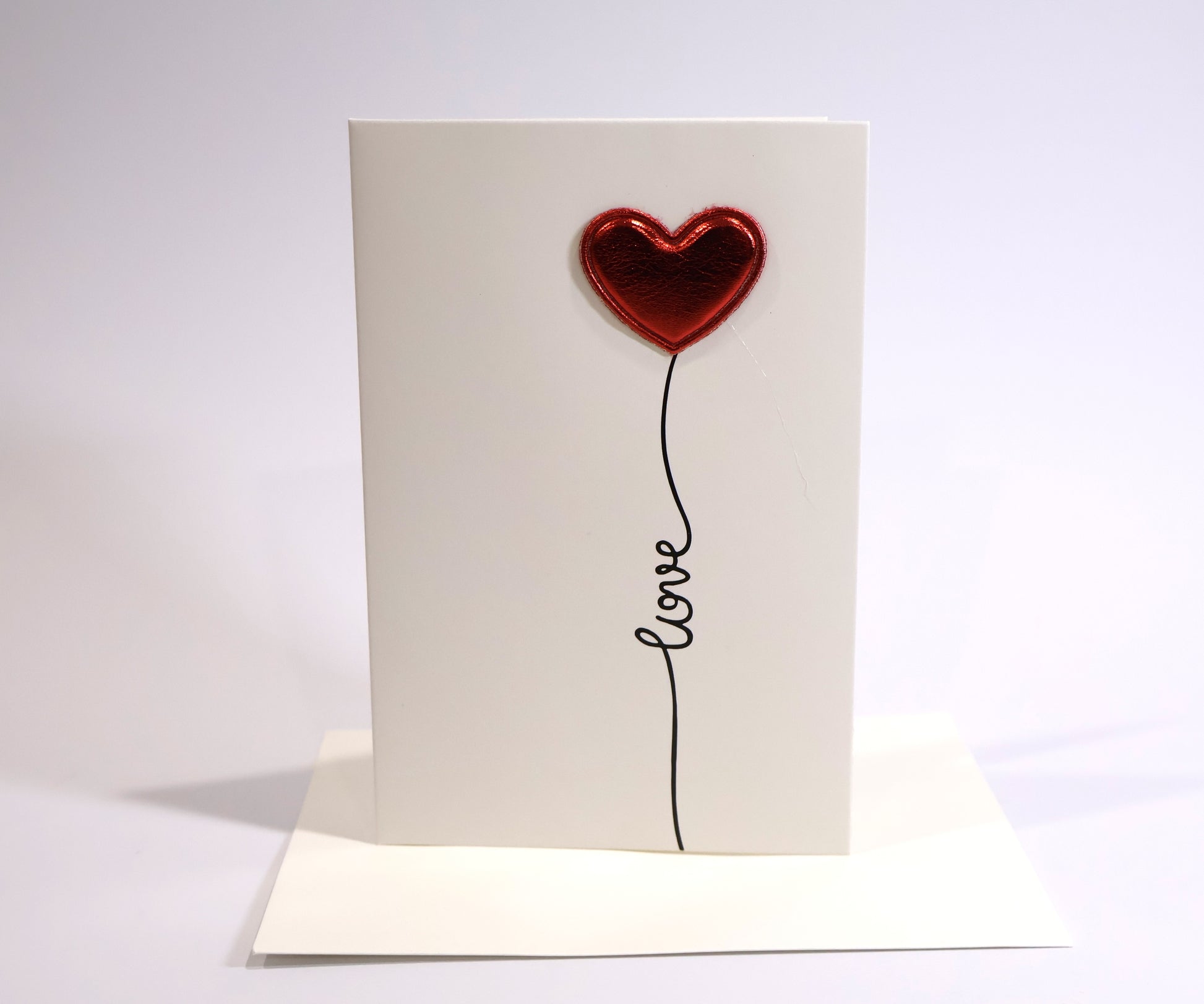 Card with a red heart-shaped balloon and 'love' text on a white background