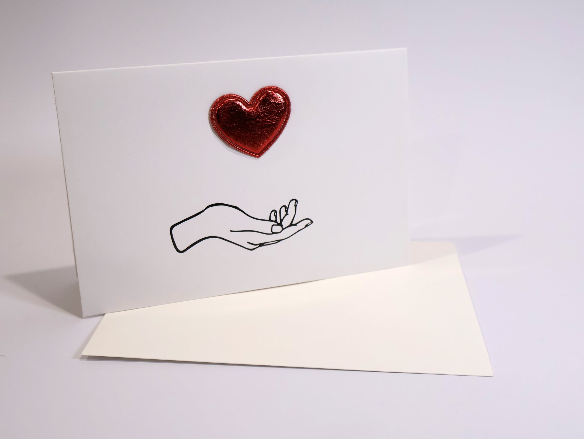 Greeting card with a red heart and a hand holding a ring on a white background