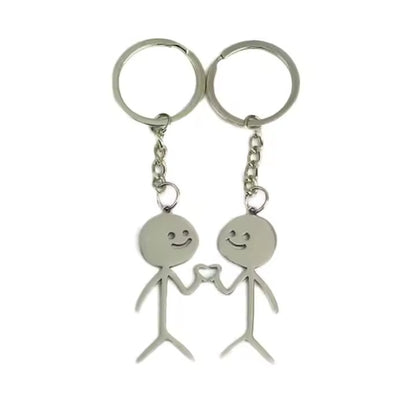 Two silver keychains shaped like stick figures holding hands on a white background