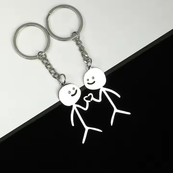 Keychain with stick figures doing heart hands design on a black and white background