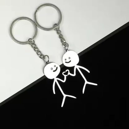 Keychain with stick figures doing heart hands design on a black and white background