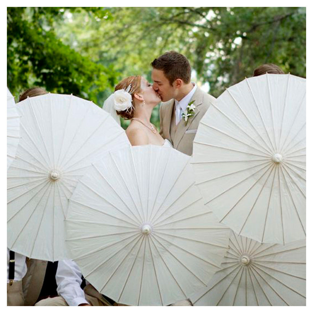 Wedding couple kissing under white parasols with a forest background