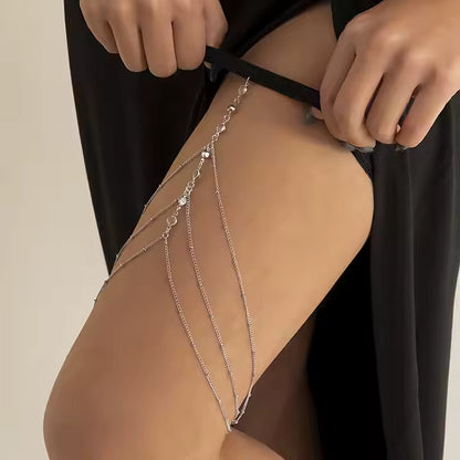 Silver leg chain bridal garter worn by a person against a neutral background