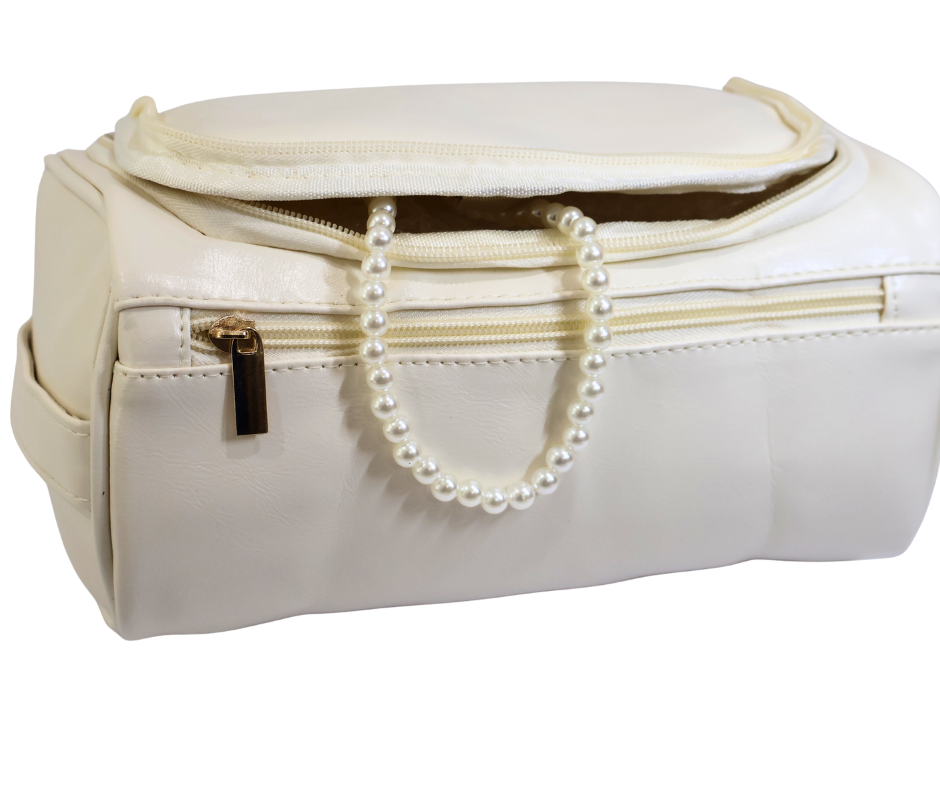 White toiletry bag with a pearl necklace draped over it on a white background