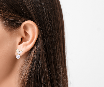 Close-up of an ear wearing a heart-shaped pearl earring with a blurred background