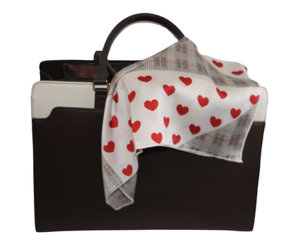 Black handbag with a white scarf featuring red heart patterns on a white background
