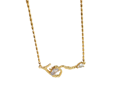 Gold necklace with a branch-shaped pendant on a white background